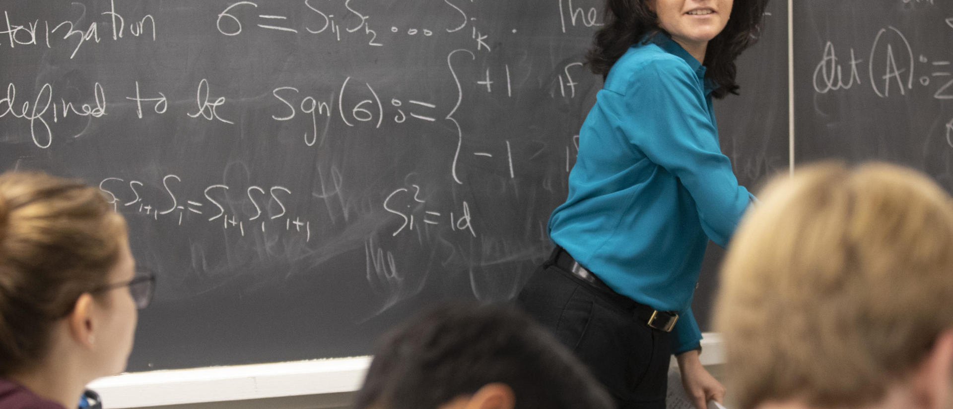 professor at chalkboard while students take notes